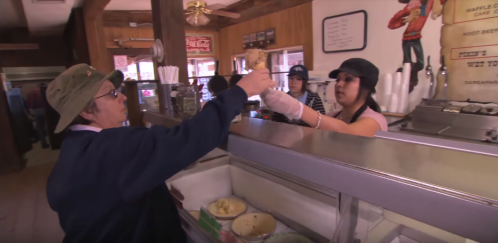 A customer receives an ice cream cone from a server at a vintage ice cream shop.