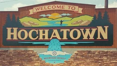 Welcome sign for Hochatown, featuring mountains, a river, and a person fishing. Mountain County, Oklahoma.