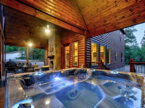 A luxurious hot tub on a wooden deck, surrounded by a rustic cabin and trees, illuminated in the evening light.