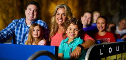 A smiling family poses together on a ride, with children in front and adults behind, all enjoying a fun outing.