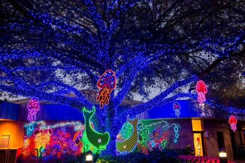 A large tree adorned with colorful lights, featuring jellyfish and sea creatures in vibrant neon colors.