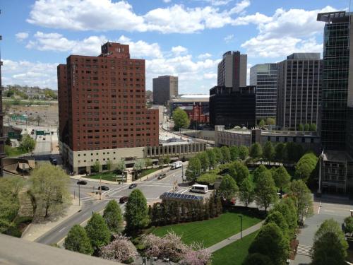 A cityscape featuring buildings, green spaces, and a blue sky with clouds.