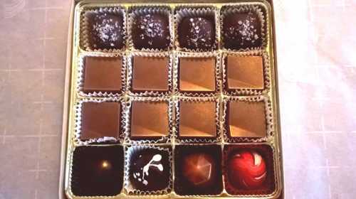 A box of assorted chocolates arranged in a grid, featuring various shapes and designs.