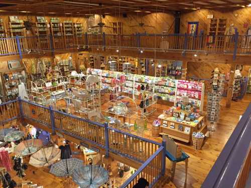 A spacious gift shop with wooden decor, featuring shelves of merchandise, colorful displays, and hanging umbrellas.