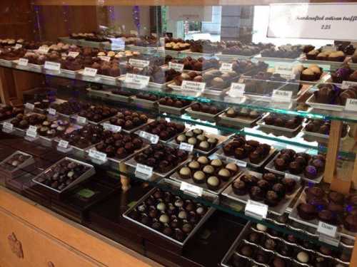 A display case filled with various types of chocolates, neatly arranged on trays with labels.