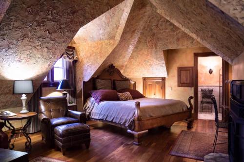 Cozy attic bedroom with sloped ceilings, a large bed, armchair, and warm lighting.