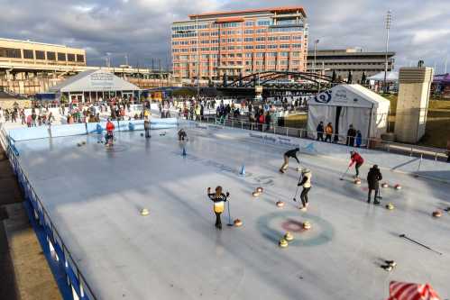 A bustling outdoor curling rink with participants and spectators, set against a backdrop of a modern building.