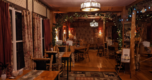 Cozy rustic dining area with wooden furniture, warm lighting, and decorative curtains, creating an inviting atmosphere.