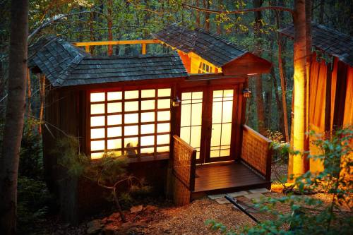 A cozy wooden cabin with illuminated windows, nestled among trees in a serene forest setting.