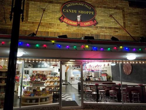Exterior of Snoqualmie Falls Candy Shoppe, featuring colorful lights, a sign, and a display of sweets inside.