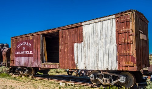 A weathered wooden train car with "Tonopah & Goldfield" painted on the side, set against a clear blue sky.