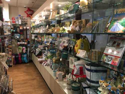 A colorful retail store aisle filled with various gift items, home decor, and accessories displayed on glass shelves.