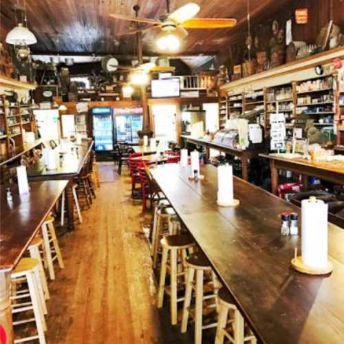 A rustic interior of a bar with wooden tables, stools, and shelves filled with various items, creating a cozy atmosphere.