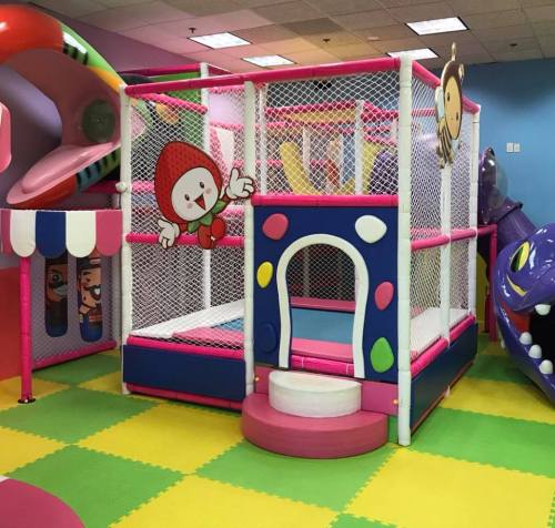 Colorful indoor play area with a mesh play structure, slides, and cartoon characters on the walls.