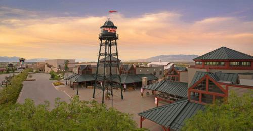 A scenic view of a shopping center featuring a tall water tower and modern buildings under a colorful sunset sky.