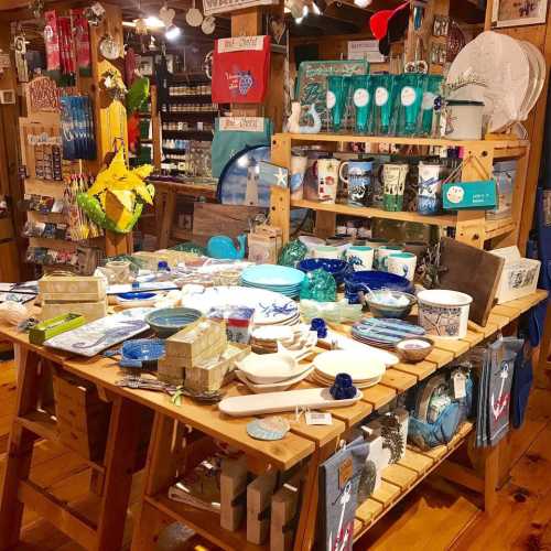 A vibrant display of various decorative items and tableware arranged on wooden tables in a cozy shop.