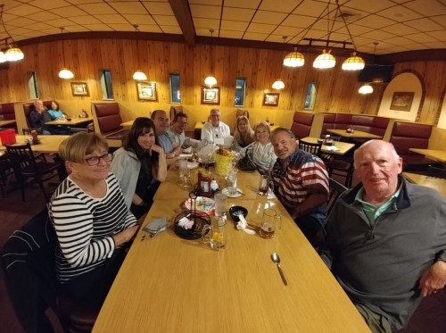 A group of nine people sitting around a table in a cozy restaurant, enjoying a meal together.