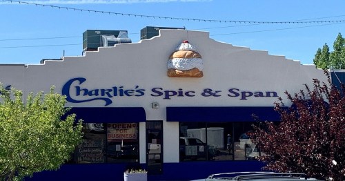 Sign for "Charlie's Spic & Span" featuring a large ice cream sundae on the roof, with a clear blue sky above.