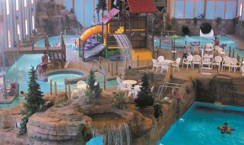 Indoor water park featuring slides, pools, and seating areas surrounded by rock formations and greenery.