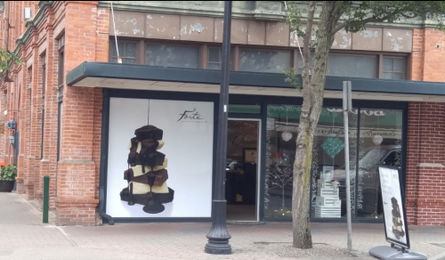 A storefront with a modern art installation hanging outside, featuring a mix of colors and shapes.