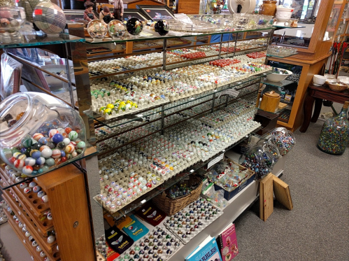 A display shelf filled with colorful marbles and glass ornaments in a shop, showcasing various sizes and designs.