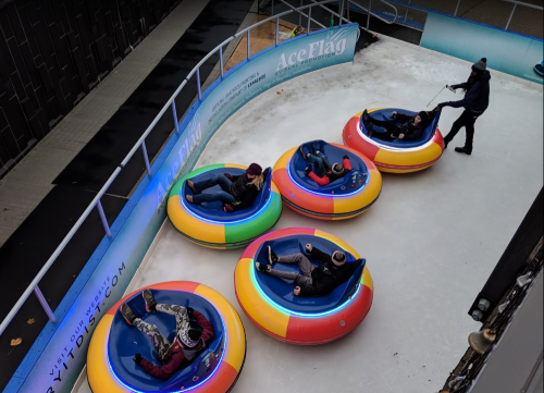 Aerial view of colorful bumper cars on ice, with people enjoying a fun activity in a winter setting.