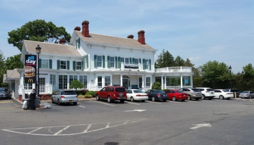 A McDonald's restaurant in a large, white, historic building with a parking lot filled with cars on a sunny day.