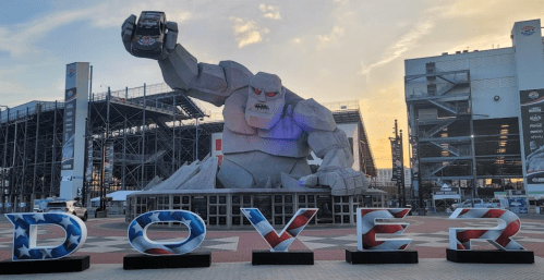 A large stone statue of a monster holding a toy car, with "DOVER" in colorful letters in the foreground.