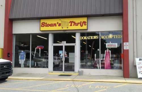 Exterior of Sloan's Thrift store with large windows, a sign for donations, and a U-Haul rental advertisement.