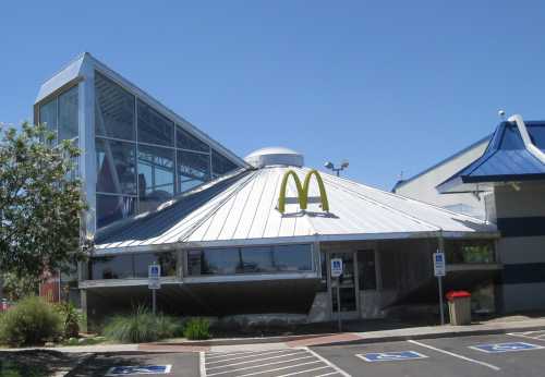 A unique McDonald's building with a modern design, featuring a sloped roof and large glass windows.