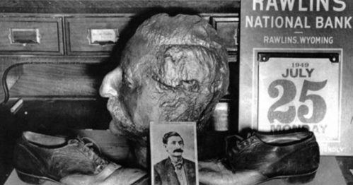 A vintage display featuring a wax head, old shoes, a photo of a man, and a calendar from July 25, 1949.