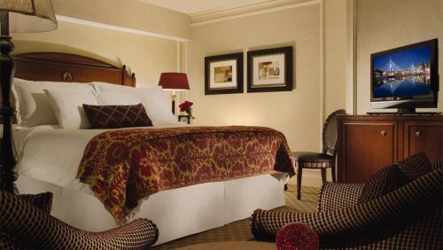 A cozy hotel room featuring a large bed, decorative pillows, a TV, and elegant furnishings.