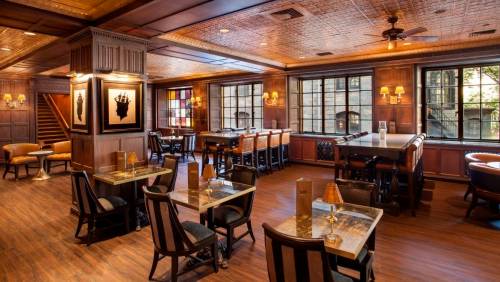 Elegant restaurant interior with wooden accents, tables, and large windows, creating a warm and inviting atmosphere.