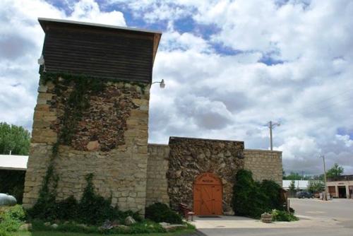 Historic stone building with a wooden roof, surrounded by greenery and under a cloudy sky.