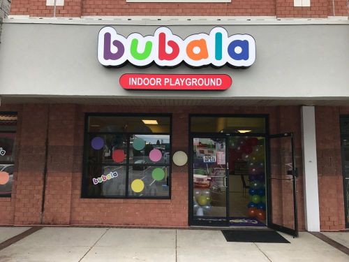 Colorful storefront of "Bubala Indoor Playground" with a welcoming entrance and balloons visible inside.