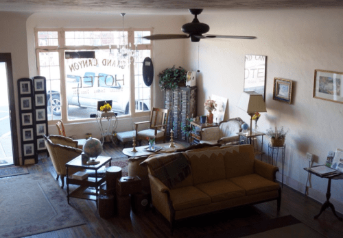 Cozy interior of a hotel lobby with vintage furniture, a globe, and large windows letting in natural light.