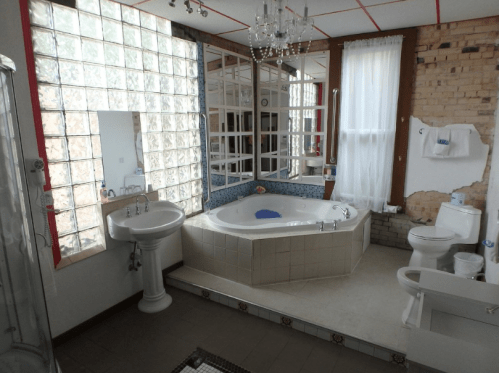 A spacious bathroom featuring a jacuzzi, glass block windows, and modern fixtures in a bright, airy setting.
