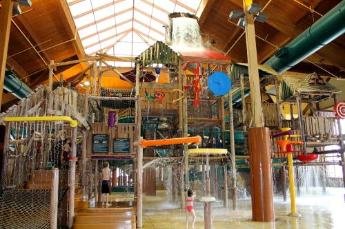 A large indoor water play area with slides, water features, and a splash zone, under a bright, open ceiling.