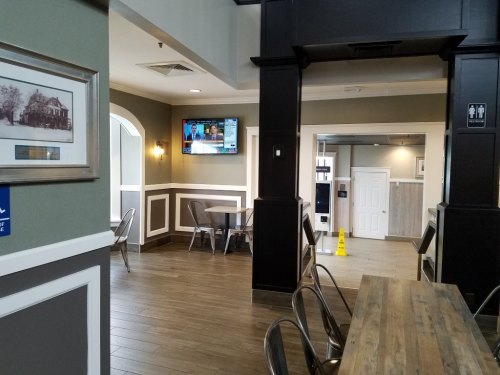 Interior of a modern building with a seating area, TV on the wall, and a caution sign on the floor.