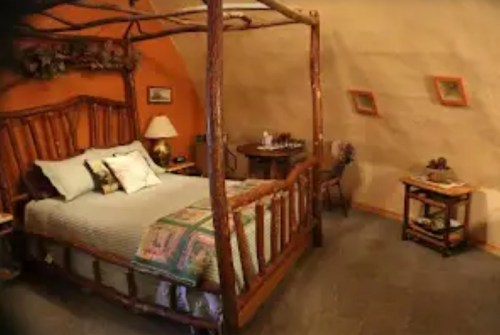 Cozy bedroom with a wooden four-poster bed, soft bedding, and rustic decor in a warm, inviting space.