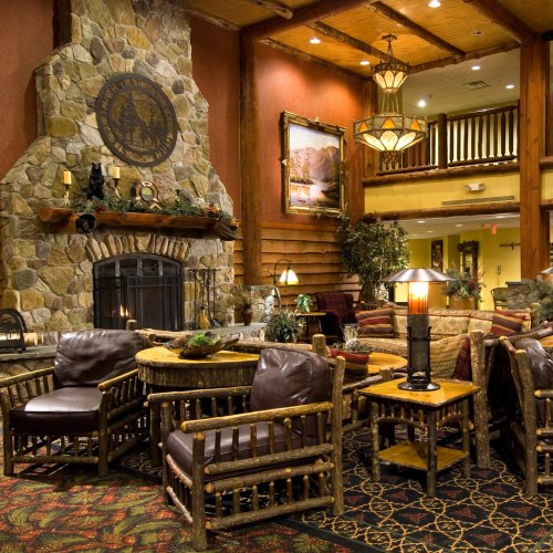 Cozy lodge interior with stone fireplace, wooden furniture, and warm lighting, creating a welcoming atmosphere.