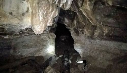 A dimly lit cave entrance with rocky walls and a narrow passage leading into darkness.