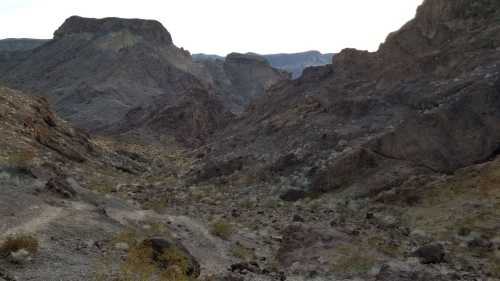 A rocky desert landscape with rugged mountains and a valley, under a clear sky.