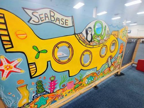 A colorful mural of a yellow submarine with a penguin and sea creatures, set against a blue ocean background.