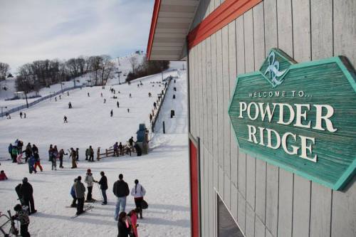 A snowy ski resort scene with people skiing and snowboarding, featuring a sign that reads "Welcome to Powder Ridge."
