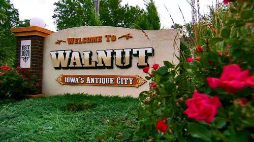 Welcome sign for Walnut, Iowa, featuring flowers and the text "Welcome to Walnut, Iowa's Antique City, Est. 1871."