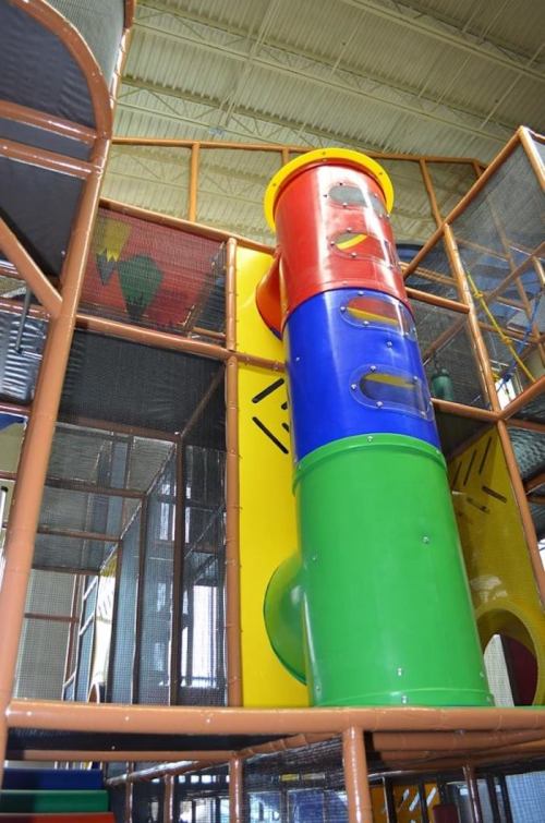 Colorful indoor playground structure featuring a tall slide and various climbing elements.