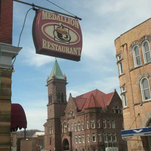 Sign for "Medallion Restaurant" with a historic building in the background and a clear blue sky.