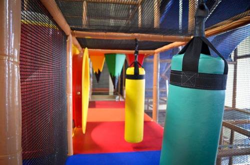 Colorful indoor play area featuring hanging bags, vibrant mats, and mesh walls for children's activities.