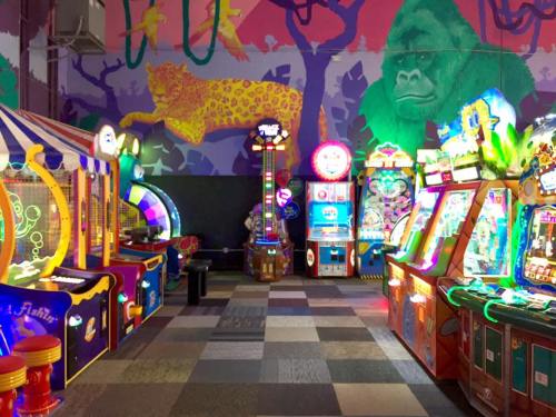 Colorful arcade with various games and a vibrant jungle mural featuring a gorilla and a leopard in the background.